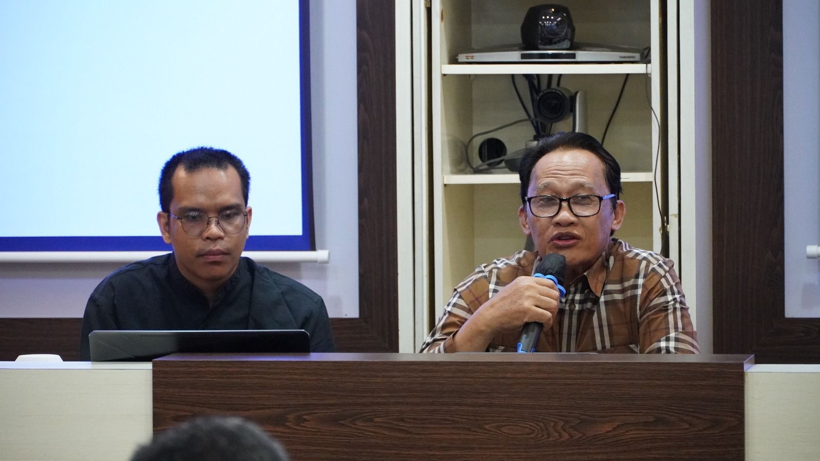 A person speaking into a microphone

Description automatically generated