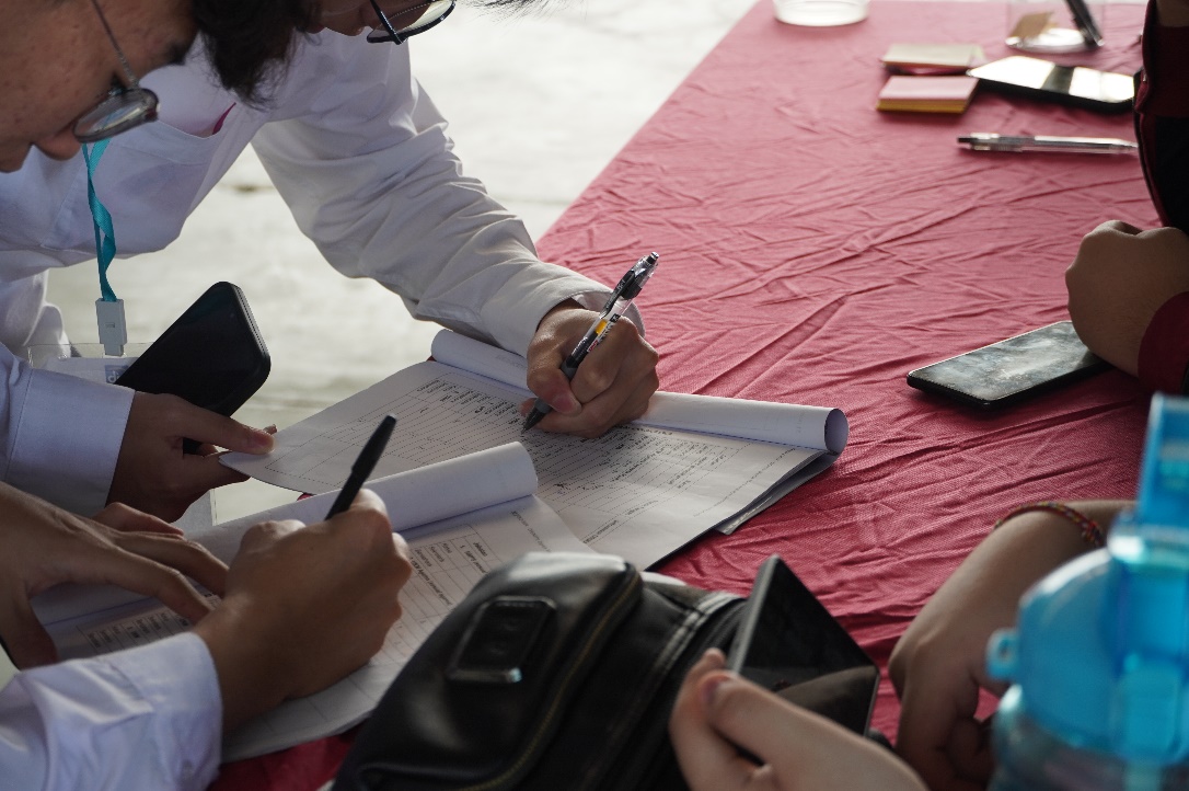 A group of people writing on a piece of paper
Description automatically generated