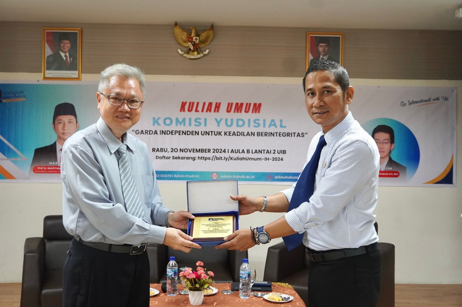 A person handing a certificate to another person Description automatically generated