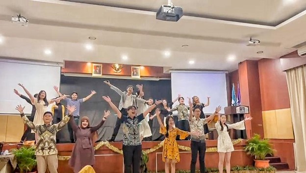 A group of people standing on a stage with their arms raised

Description automatically generated
