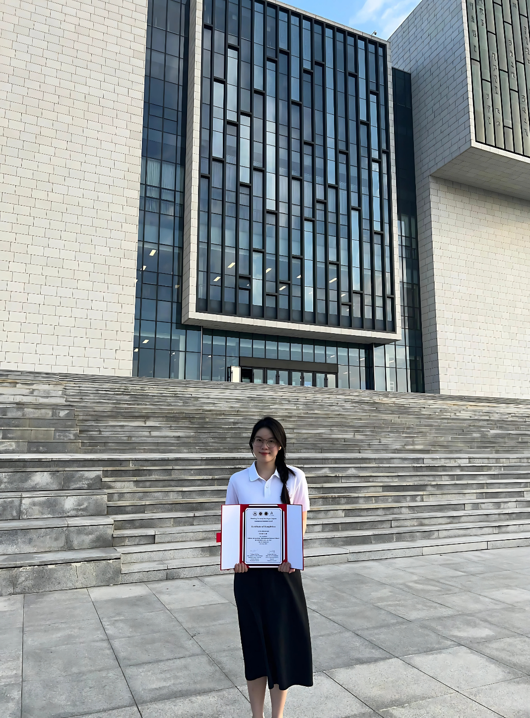 A person holding a certificate in front of a building

AI-generated content may be incorrect.