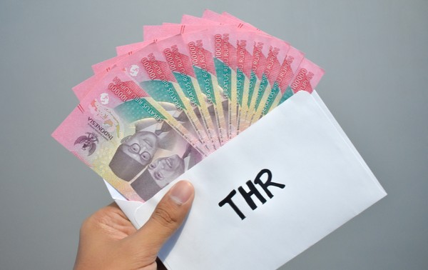 A hand holding a envelope full of money AI-generated content may be incorrect.