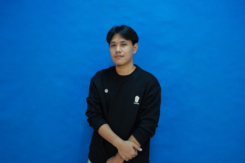 A person standing in front of a blue wall AI-generated content may be incorrect.