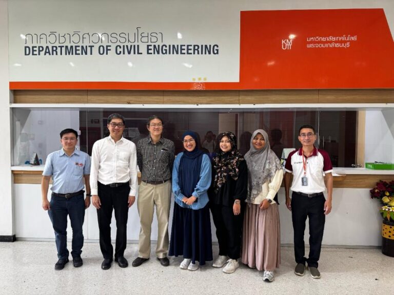 A group of people standing in front of a sign Description automatically generated