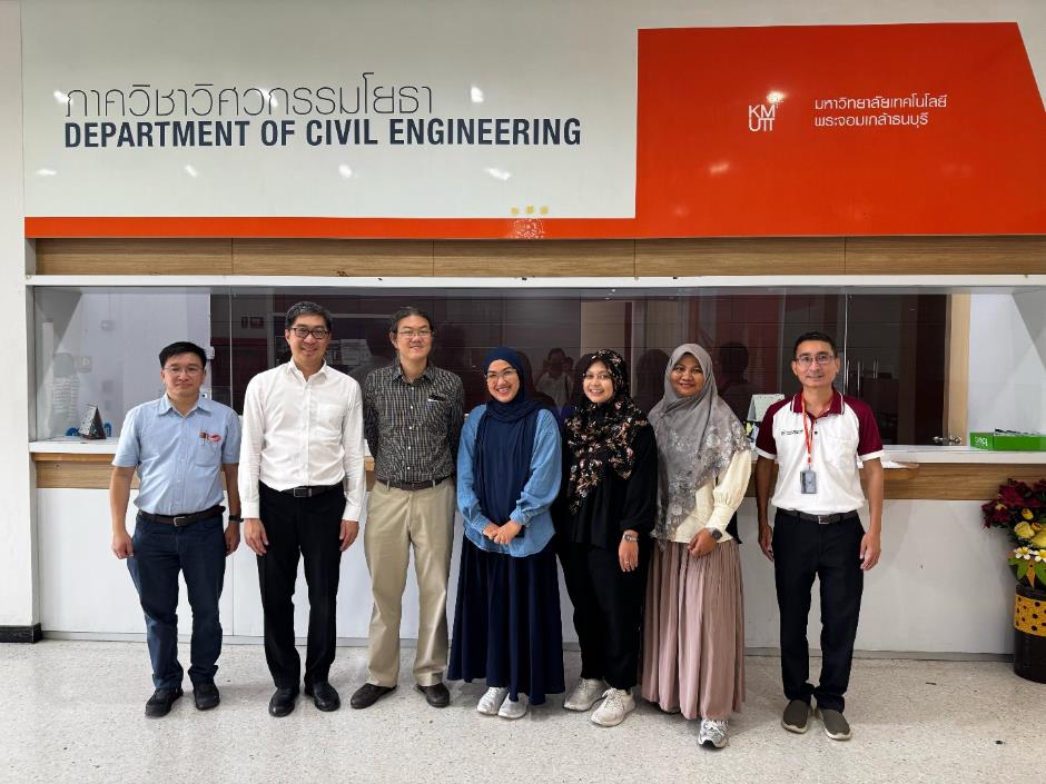 A group of people standing in front of a sign Description automatically generated