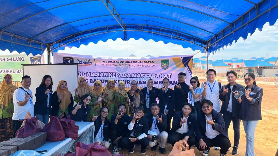 A group of people posing for a photo under a blue tent

Description automatically generated