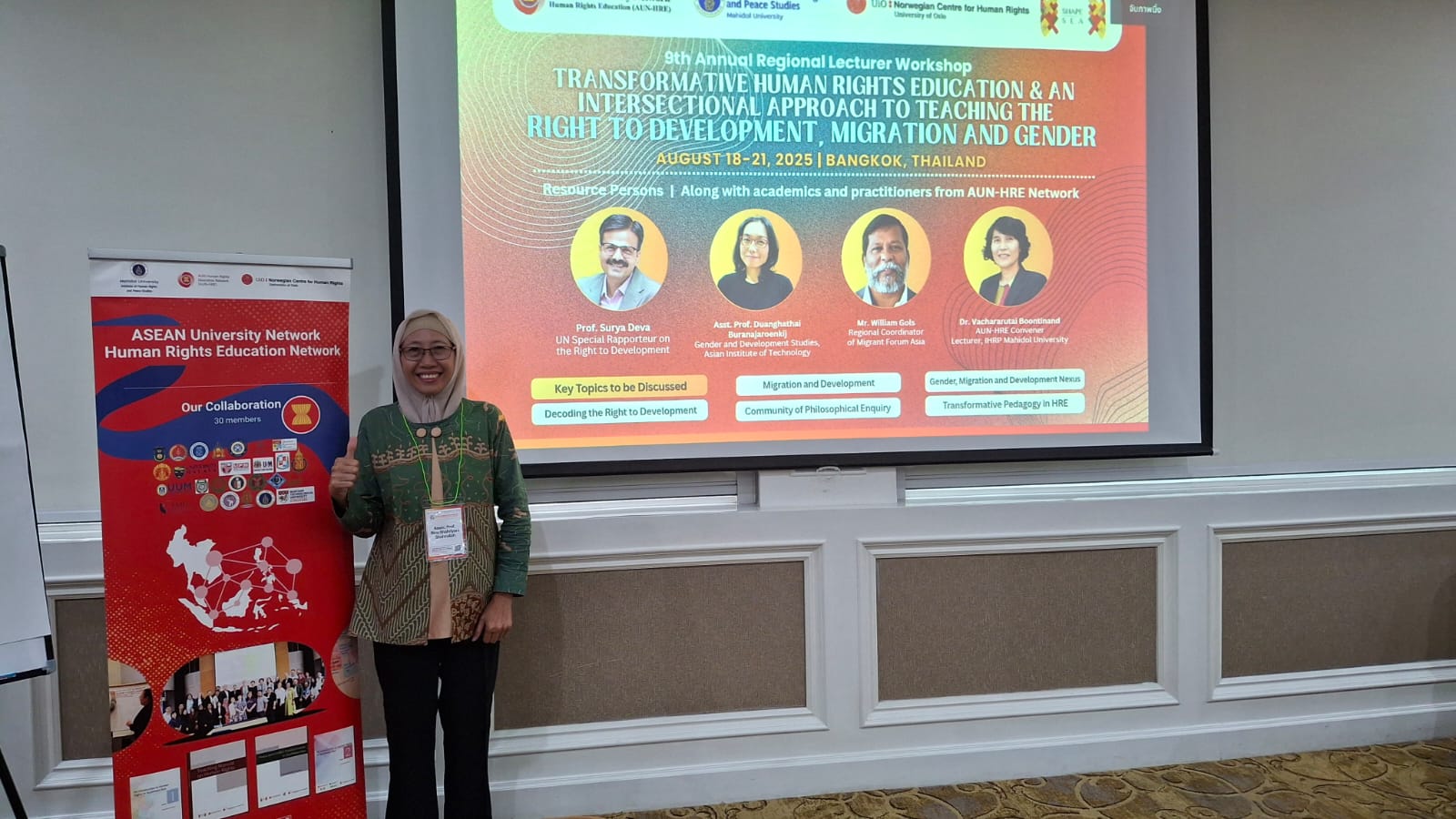 A group of people standing in front of a large projector screen

Description automatically generated
