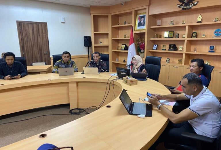 A group of people sitting at a round table with laptops Description automatically generated