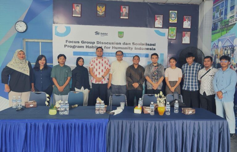 A group of people standing in front of a blue table Description automatically generated