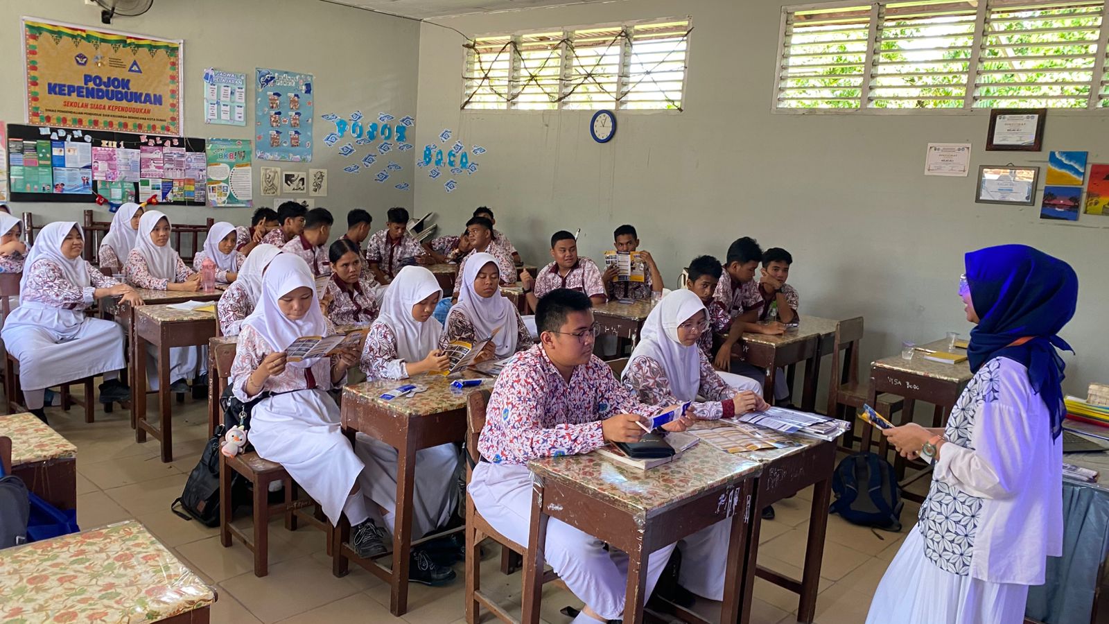 A group of people sitting at desks in a classroom Description automatically generated