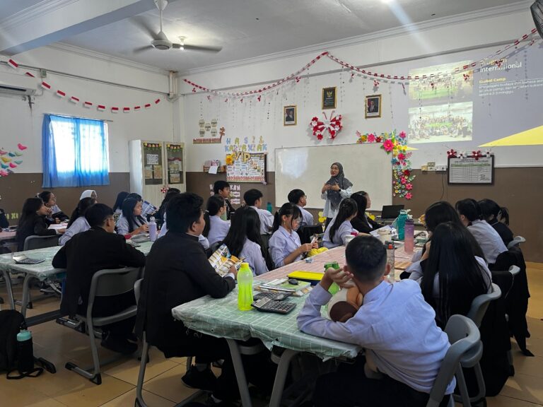 A group of people sitting at tables in a classroom Description automatically generated