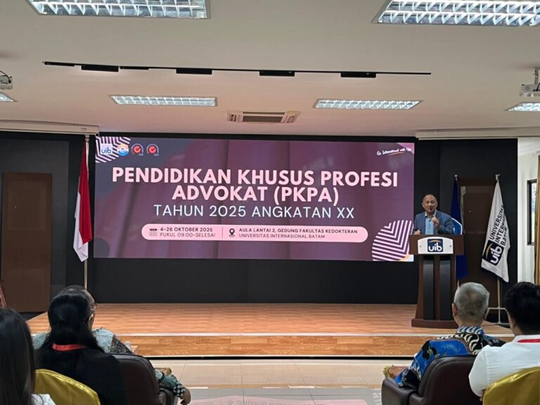 A person standing at a podium with a large screen Description automatically generated