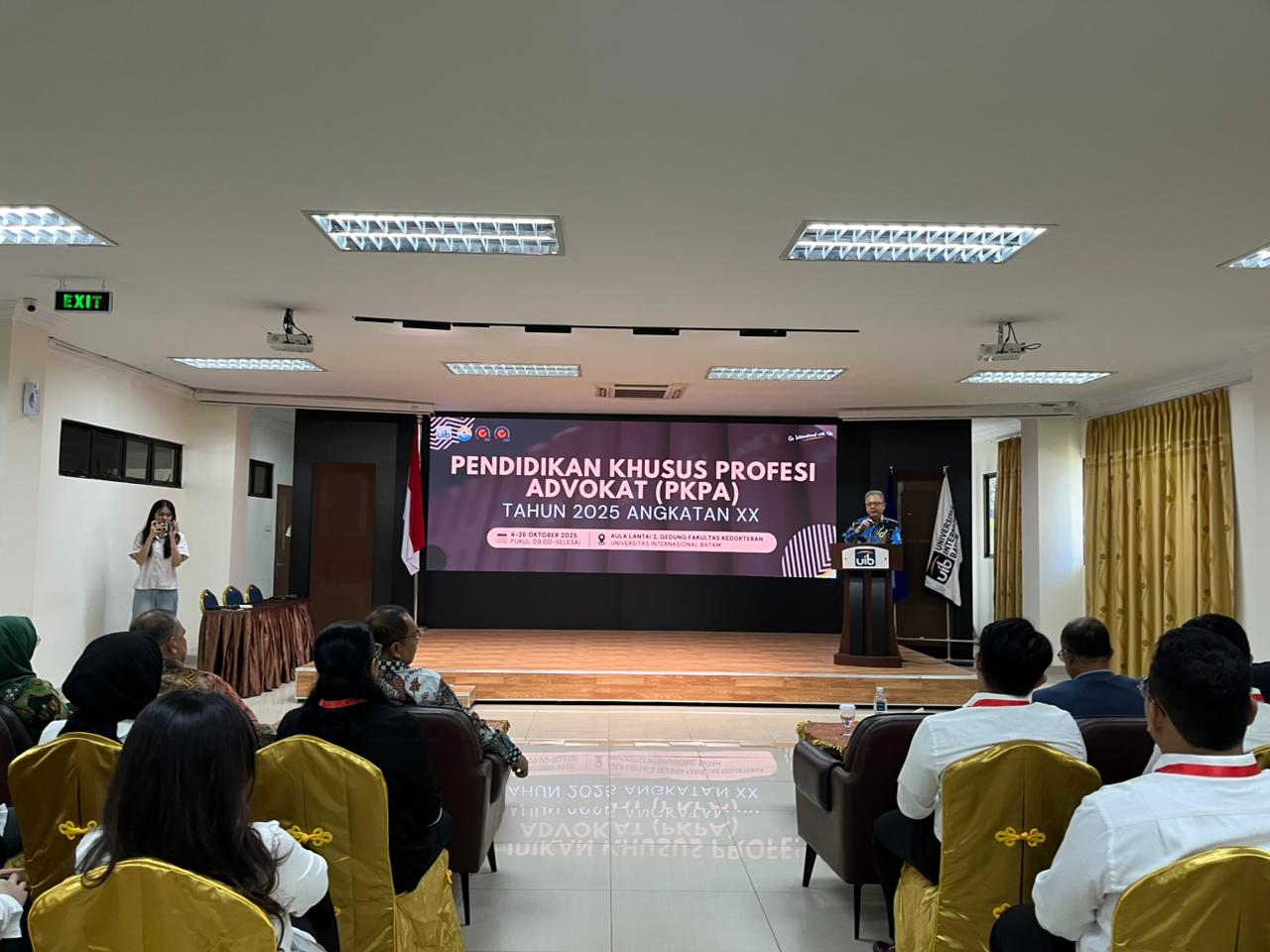 A person standing on a podium in front of a group of people

Description automatically generated