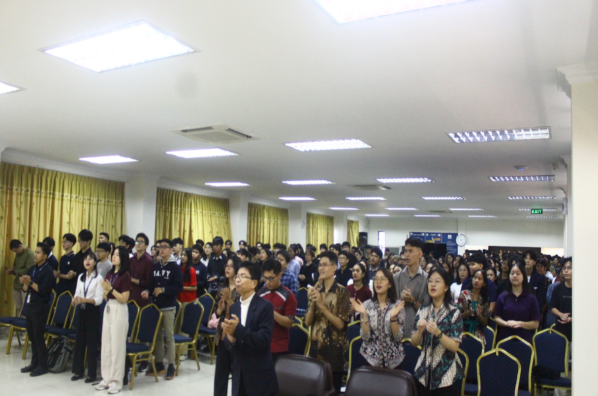 A group of people clapping in a room Description automatically generated