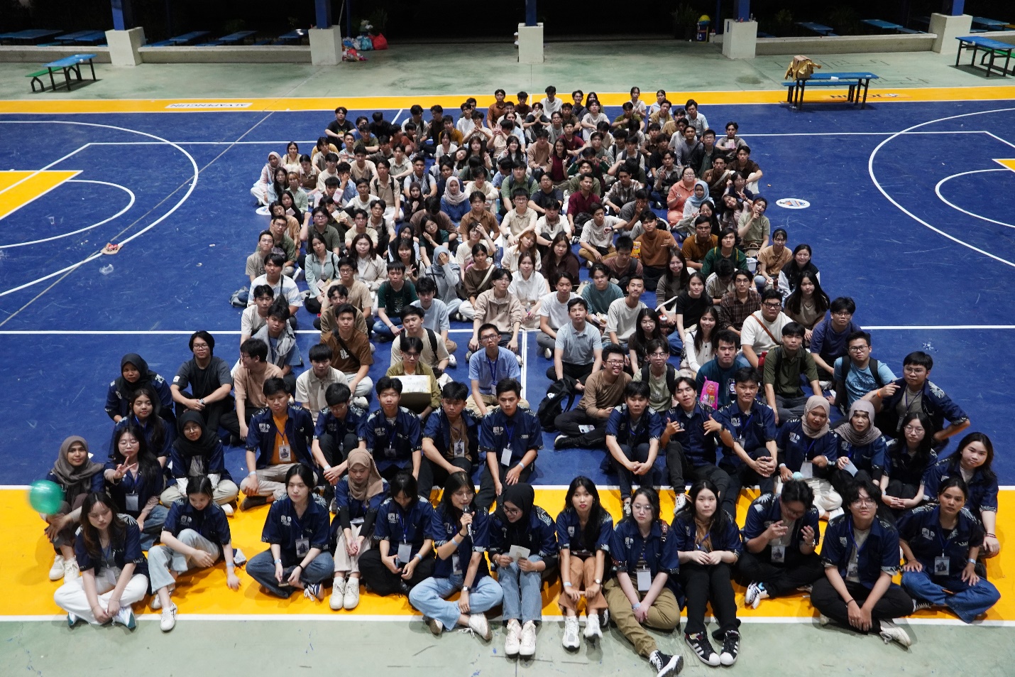 A group of people sitting on a blue and yellow floor
AI-generated content may be incorrect.