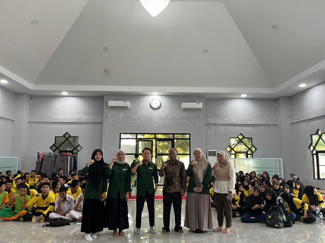 A group of people standing in a room with a group of people sitting

Description automatically generated