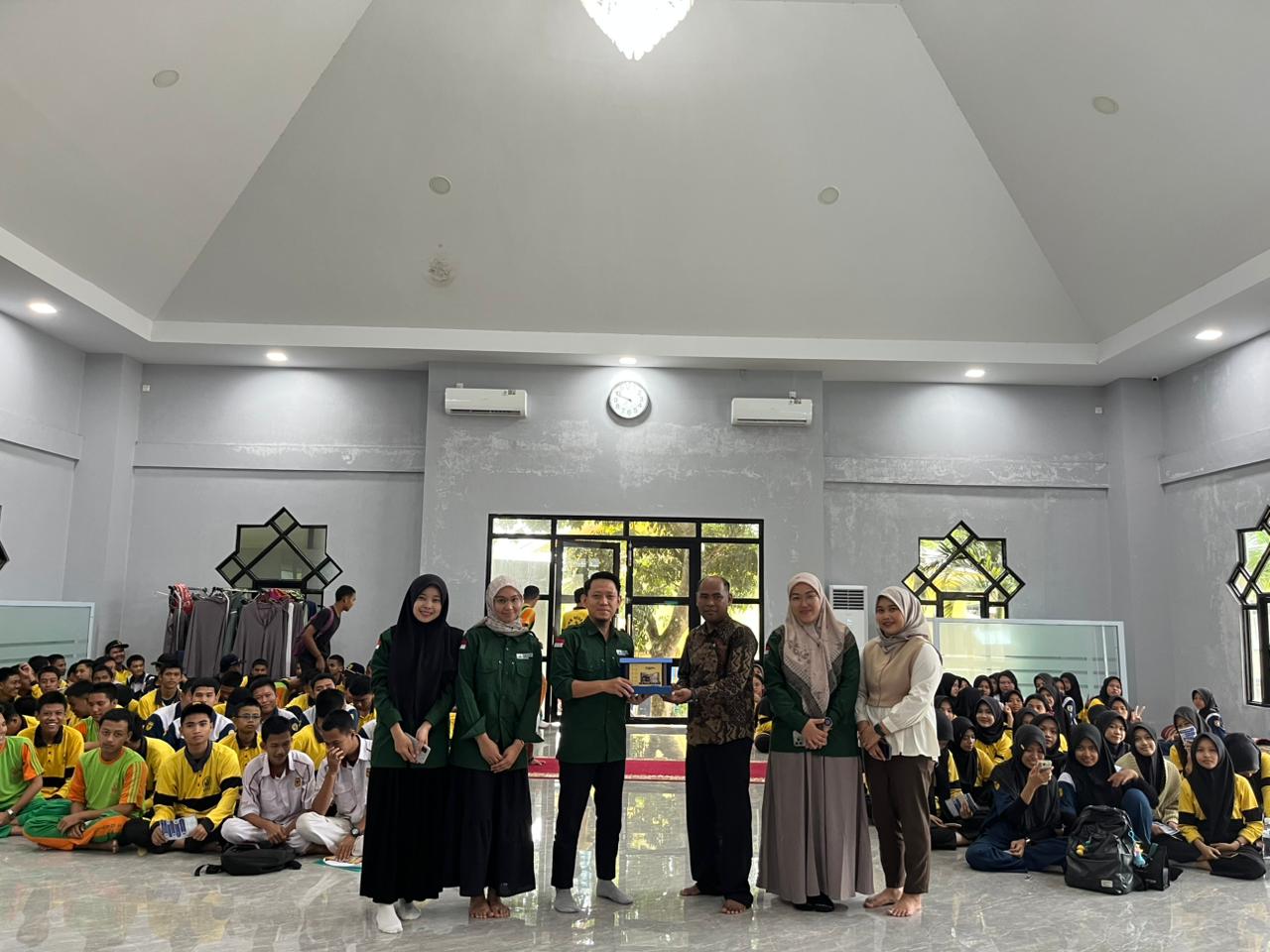 A group of people standing in a room with a group of people sitting

Description automatically generated