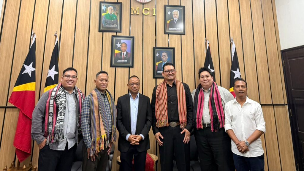 A group of men standing in front of a wall with flags Description automatically generated