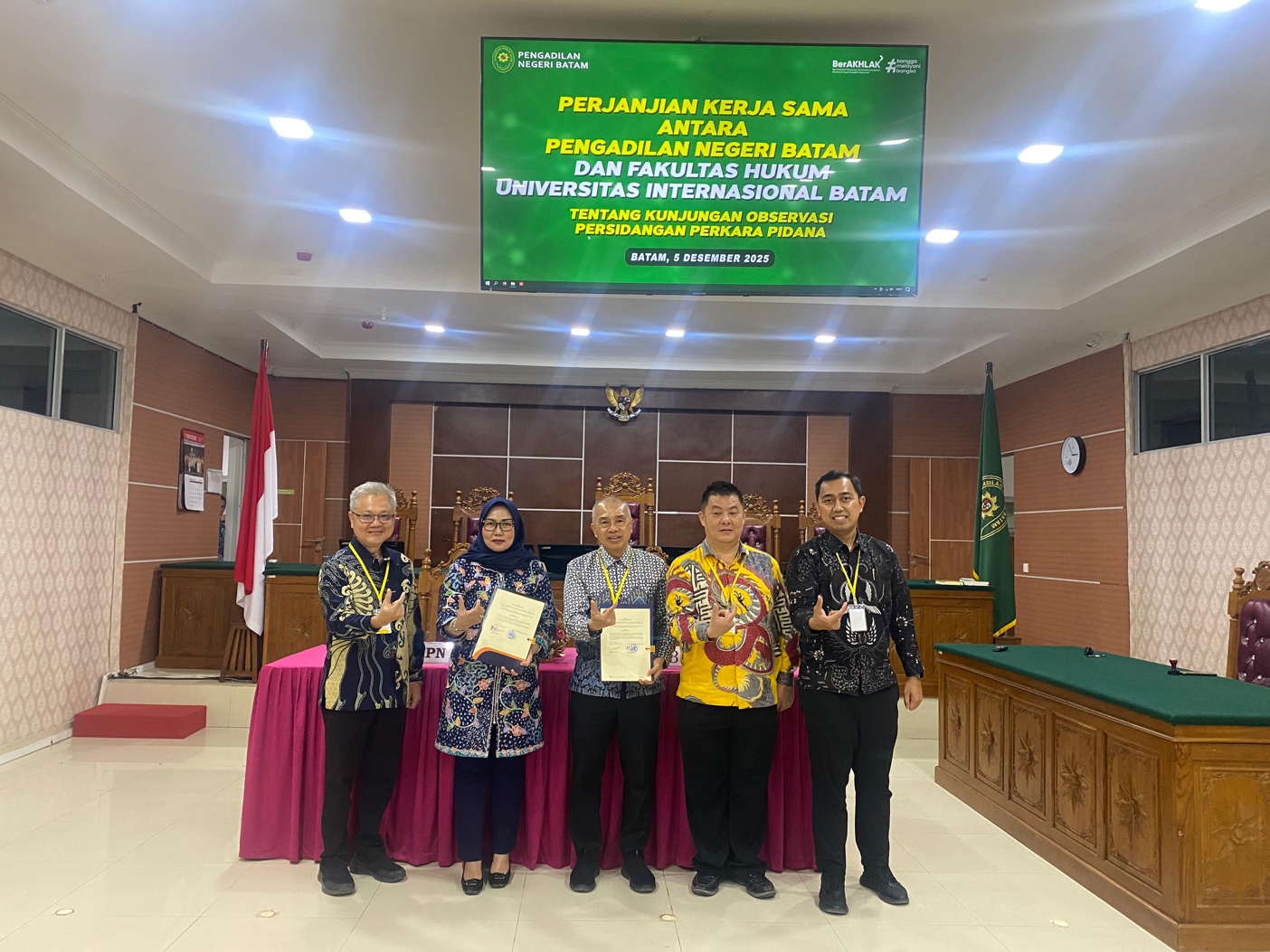 A group of people standing in front of a sign

Description automatically generated