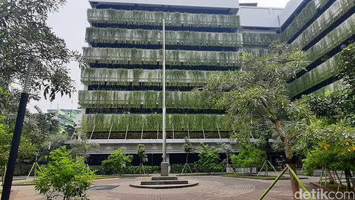 A building with a flag pole and trees Description automatically generated