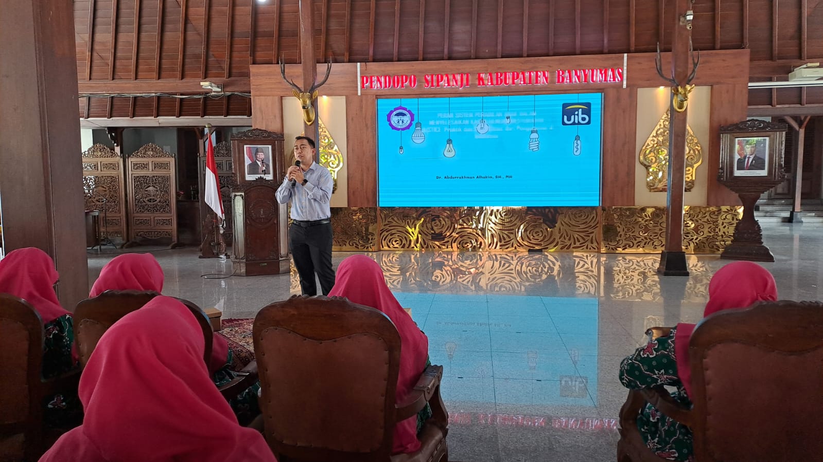 A person standing in front of a screen
Description automatically generated