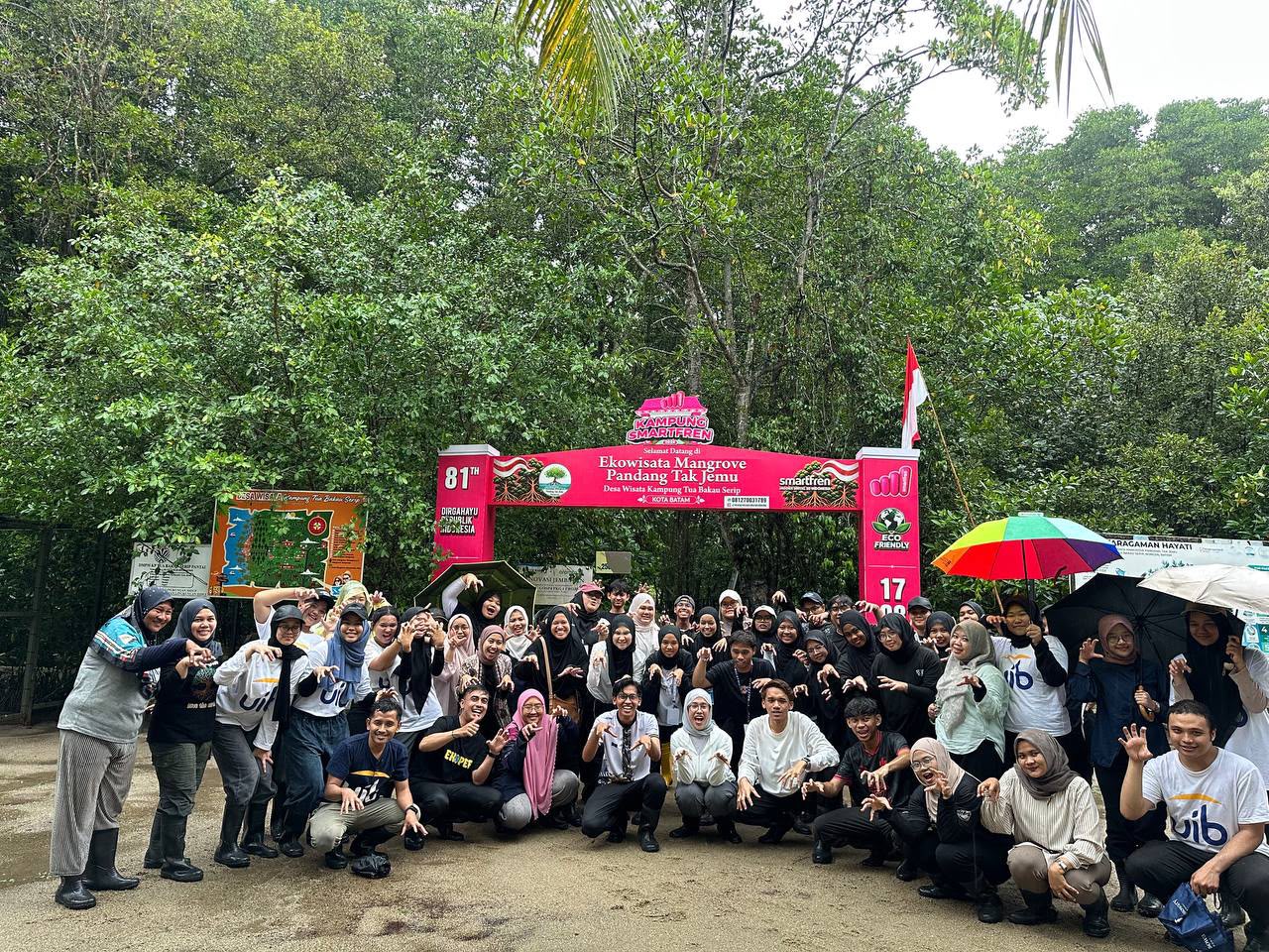 The image shows a group of people standing under a banner with a palm tree in the background, possibly in a tropical or coastal environment. AI-generated content may be incorrect.